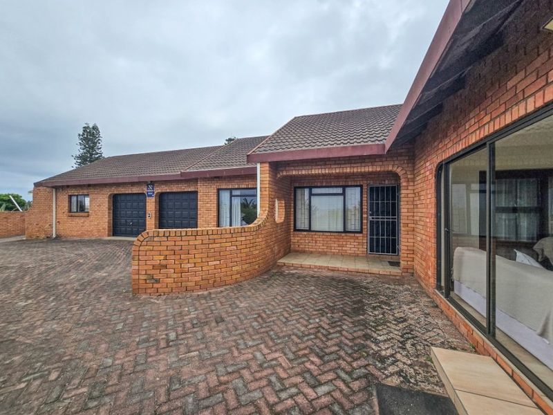 Front exterior view of a face brick house featuring a paved driveway, double garage, and sliding glass door access.