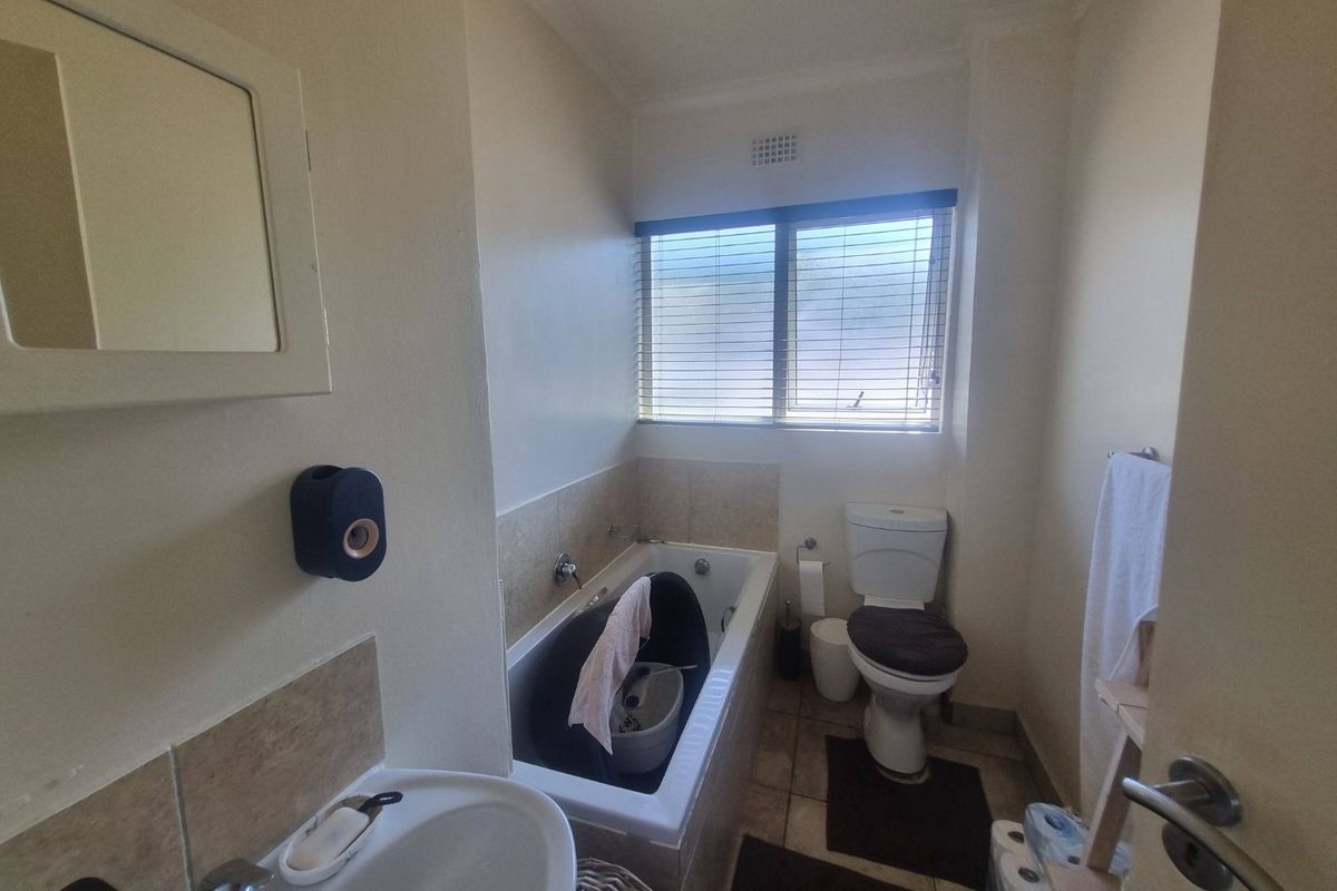 A functional bathroom featuring a bathtub, toilet, and washbasin with a medicine cabinet and tiled splashback.