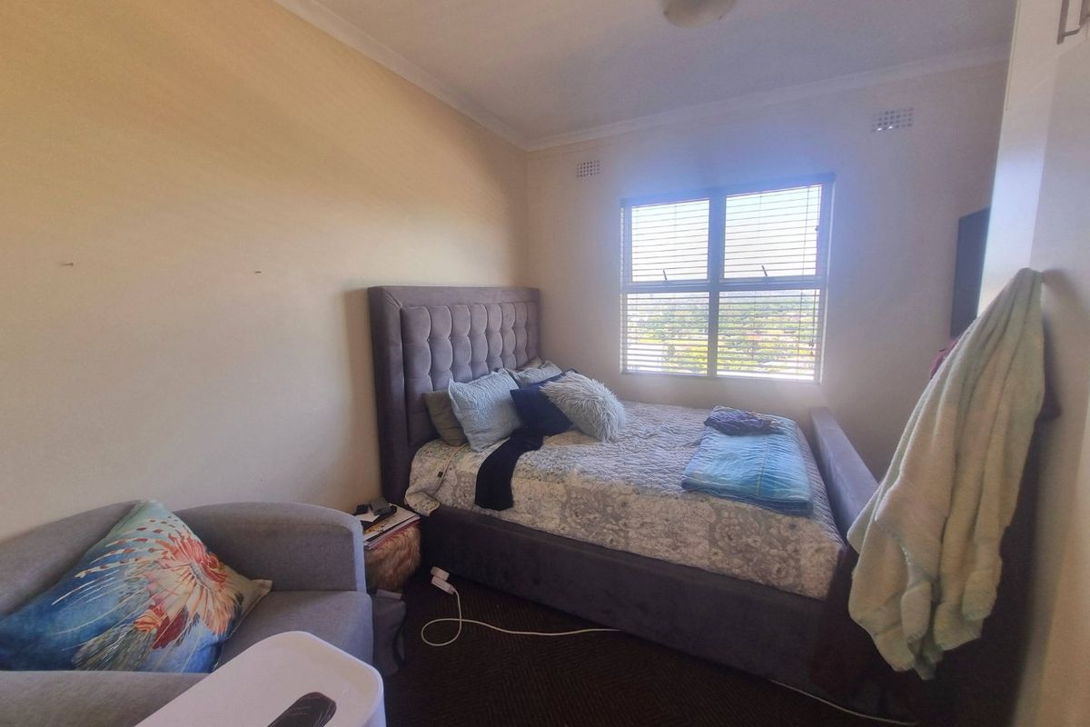 A standard bedroom featuring a window with venetian blinds, built-in cupboard storage, and cove cornice detailing.