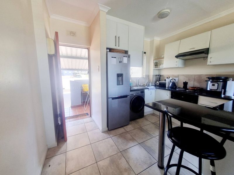 A functional kitchen featuring built-in cabinetry, granite countertops, tiled flooring, and a breakfast nook, with direct access to an outdoor patio area.