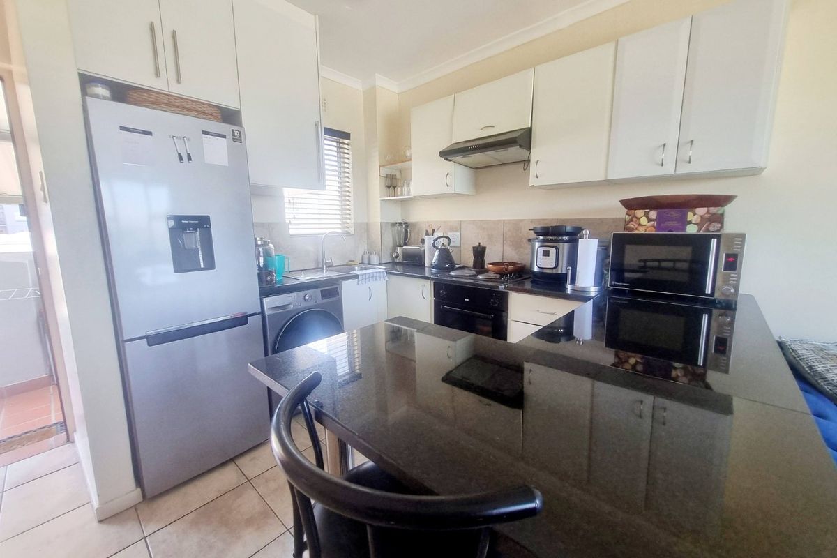 A functional kitchen featuring granite countertops, white cabinetry, built-in oven, extractor fan, and tiled flooring, offering a practical layout for daily use.