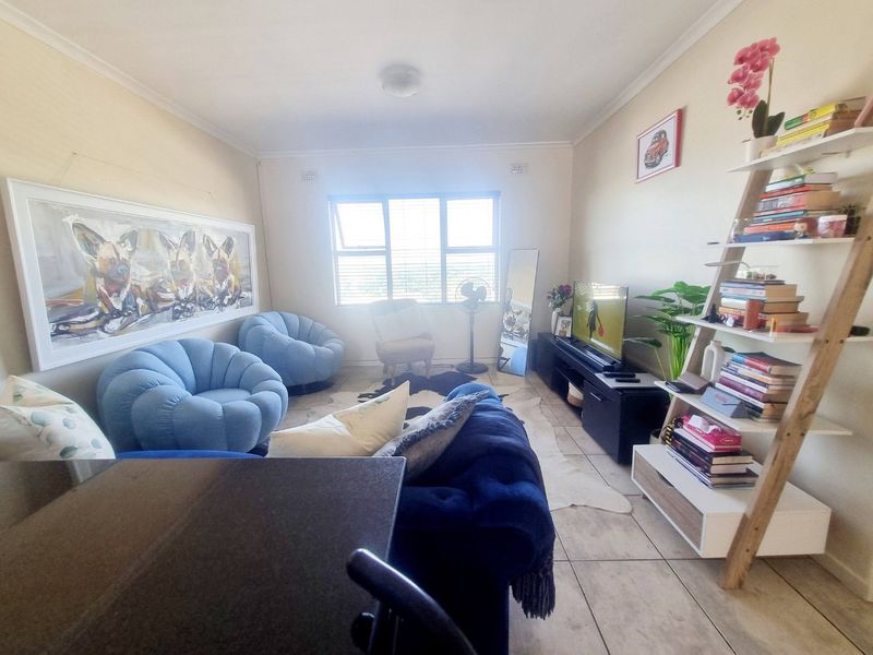 A comfortable living room featuring tiled flooring and a large window that allows for natural light.