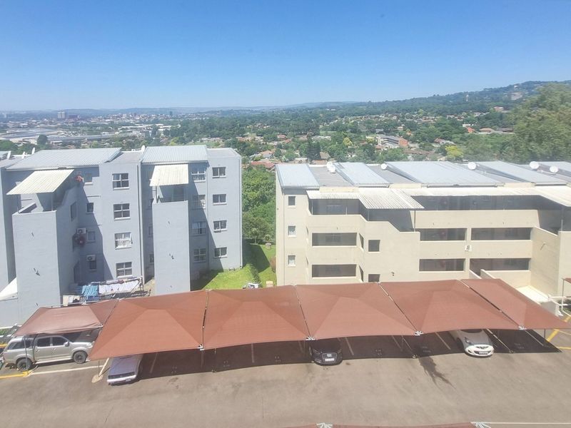 Elevated view overlooking the apartment complex grounds, featuring covered parking bays and surrounding residential buildings.