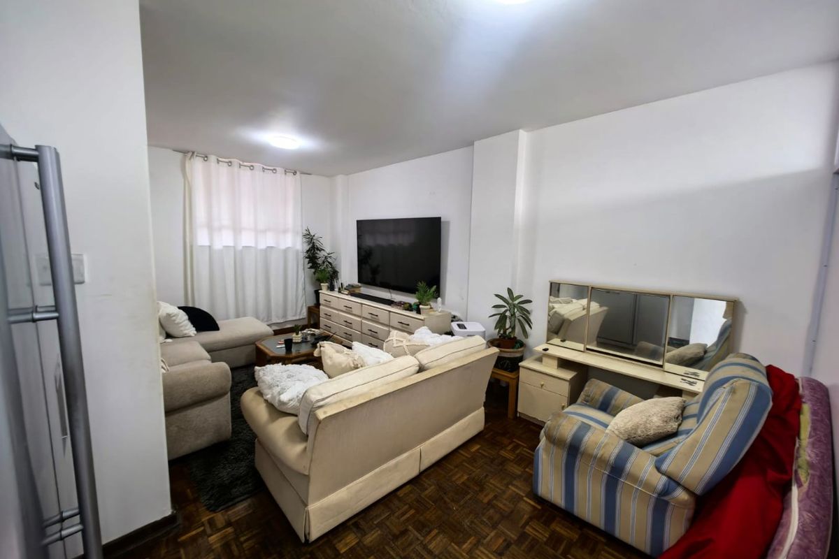 A living room featuring traditional parquet flooring and neutral wall finishes, providing a functional and comfortable space for relaxation.