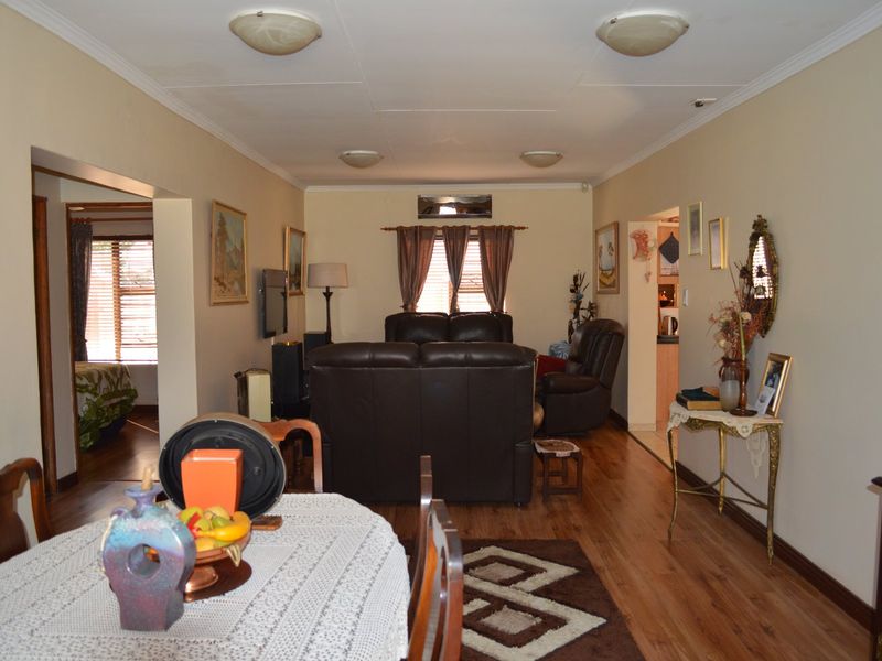 Open plan living and dining area featuring laminate flooring, coved ceilings, and an integrated air conditioning unit.