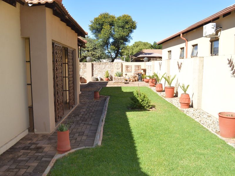 A well-maintained rear garden featuring a paved walkway, manicured lawn, and secure boundary walls, providing a private outdoor space for the townhouse.
