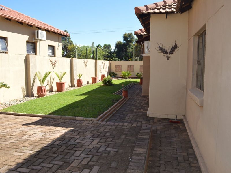 A well-maintained rear garden featuring a paved patio area, a neat lawn, and secure boundary walls, providing a private outdoor space.