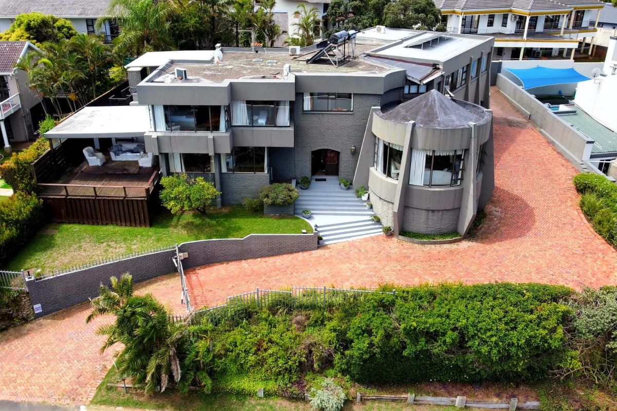 Aerial view of a multi-level residential property featuring a brick driveway, timber deck, and flat roof design with solar water heating infrastructure.