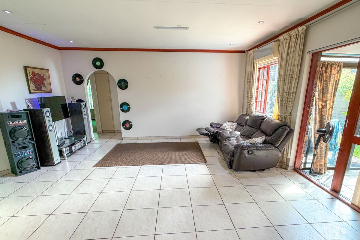 Spacious living room featuring ceramic floor tiles, recessed lighting, and large sliding glass doors providing access to the outdoor area.