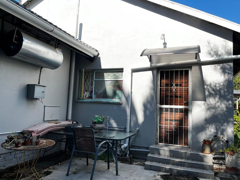 Rear exterior view of the property featuring a security gate, tiled entrance steps, and an external electric geyser unit.