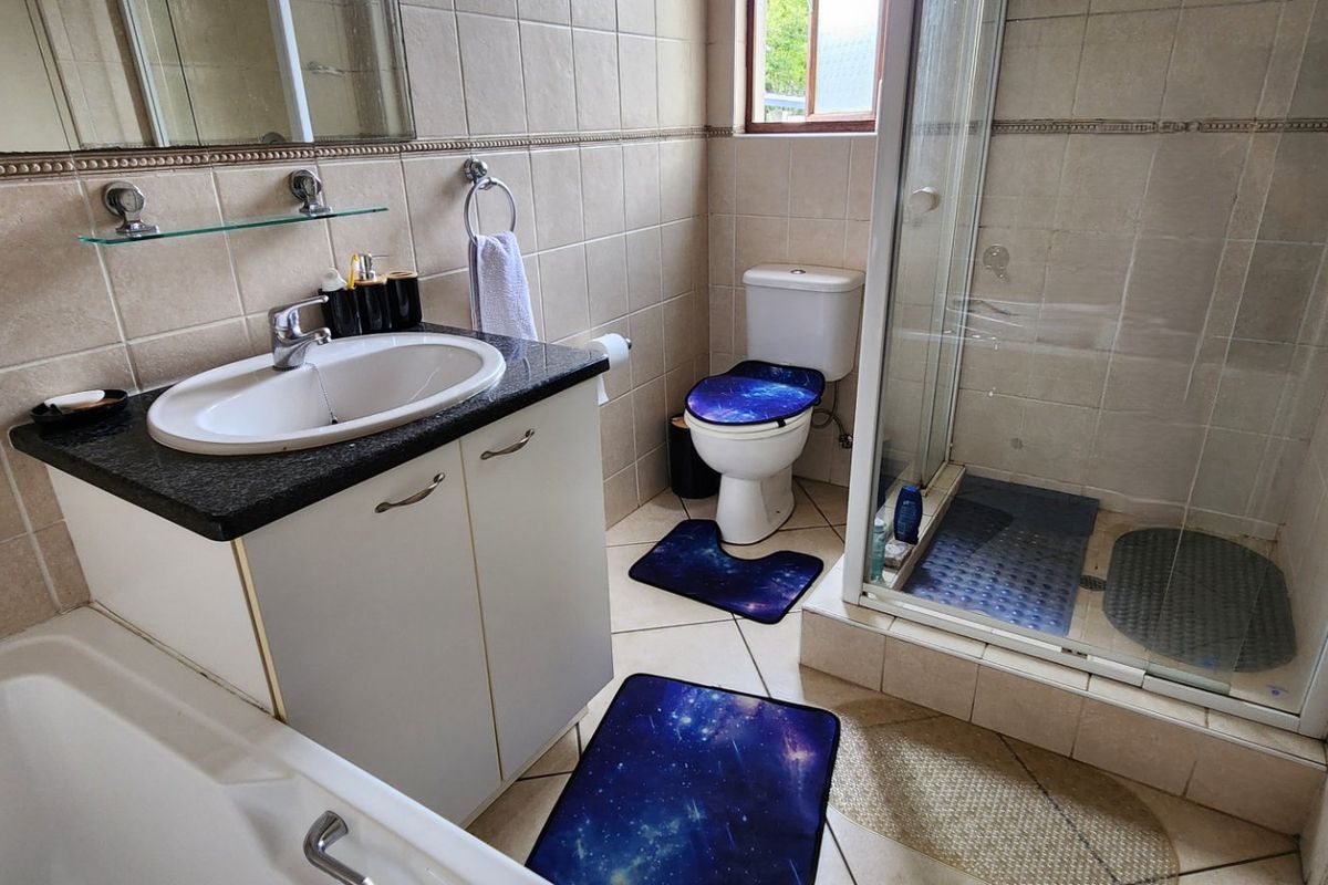 A functional bathroom featuring a vanity with granite countertop, a separate shower enclosure, and a bathtub with neutral wall and floor tiling.