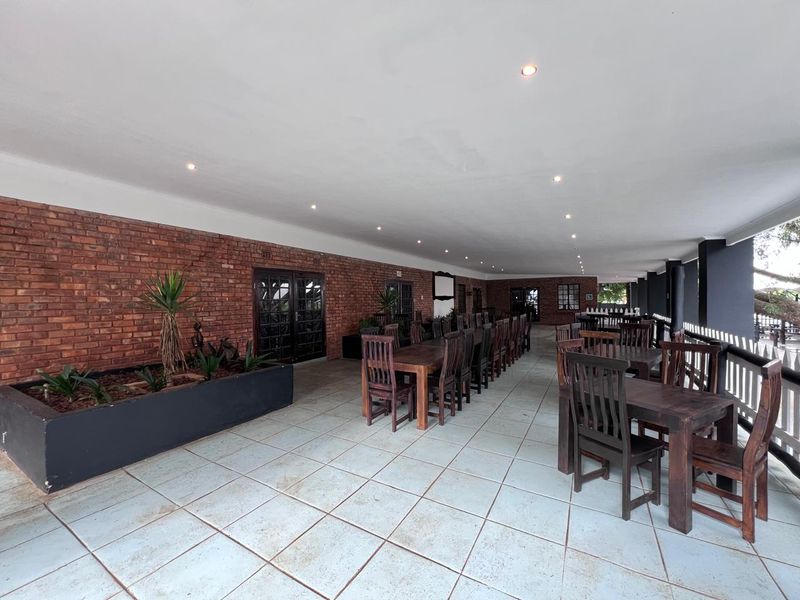 Spacious covered patio featuring exposed brick walls, recessed lighting, and built-in planter boxes, suitable for outdoor dining or commercial event hosting.