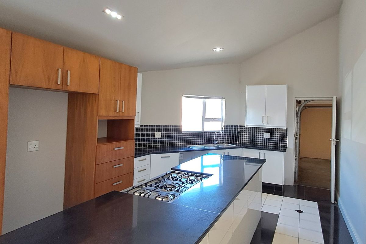 Modern kitchen featuring a central island with a gas hob, ample built-in cabinetry, tiled backsplash, and a double sink.