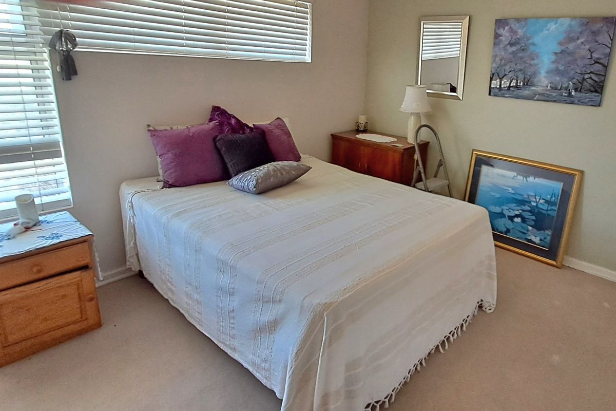 A carpeted bedroom featuring venetian blinds and neutral wall finishes, offering a functional and comfortable living space.