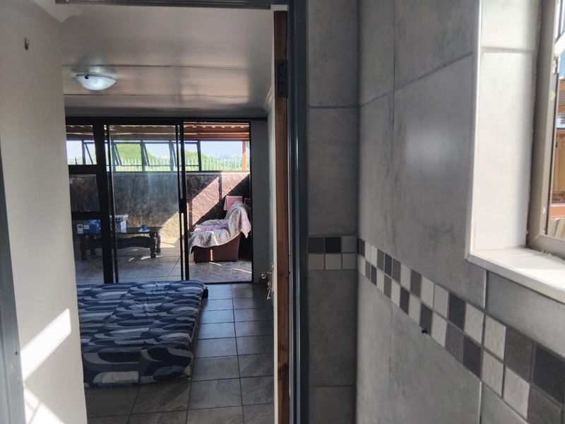 A bedroom featuring tiled flooring and sliding glass doors leading to an outdoor patio area, with tiled wall finishes visible in the foreground.