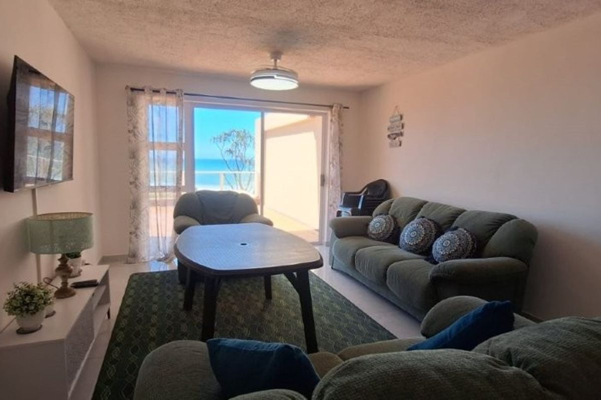A comfortable living room featuring a ceiling fan and large sliding glass doors that provide natural light and access to an outdoor balcony area.
