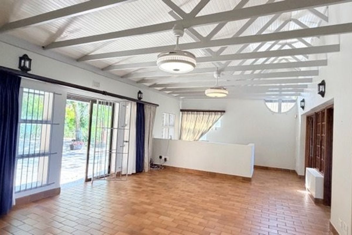 Spacious living area featuring high exposed beam ceilings, terracotta tile flooring, and large sliding glass doors providing access to the outdoor space.