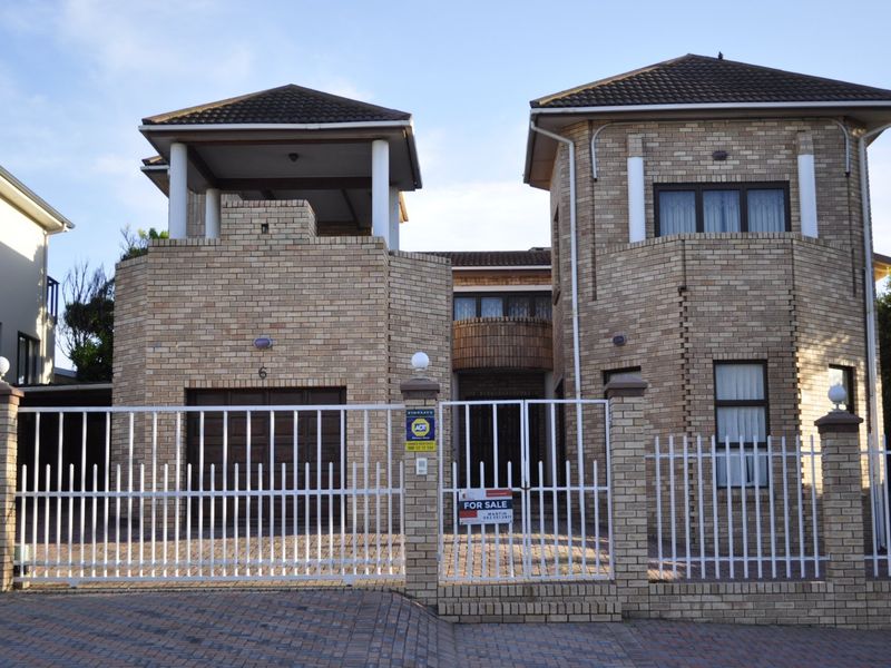A double-storey face brick residence featuring a balcony, secure gated entrance, paved driveway, and integrated garage.