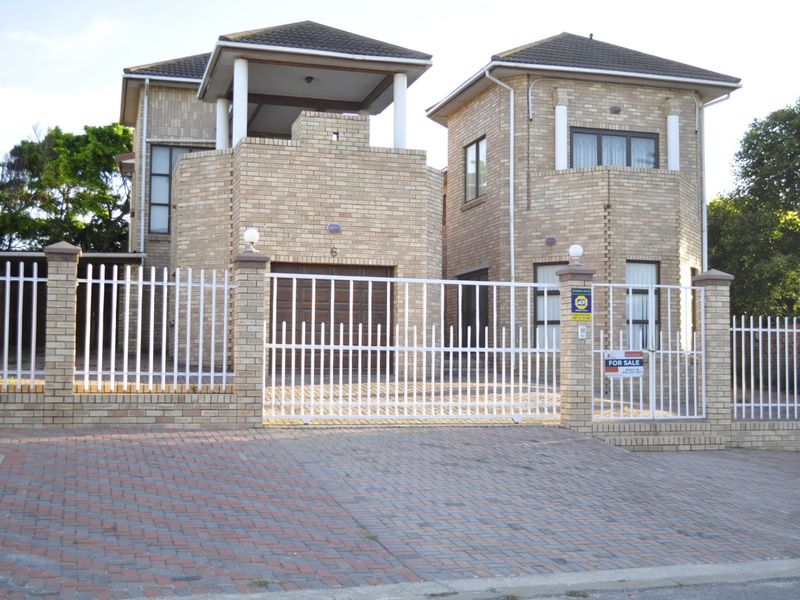 A double-storey face brick residential property featuring a paved driveway, secure perimeter fencing, and an integrated garage.