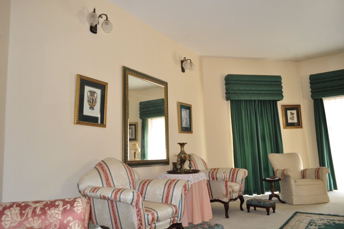 A traditional living room featuring wall-mounted light fixtures and decorative curtain pelmets, offering a classic aesthetic with neutral wall tones.