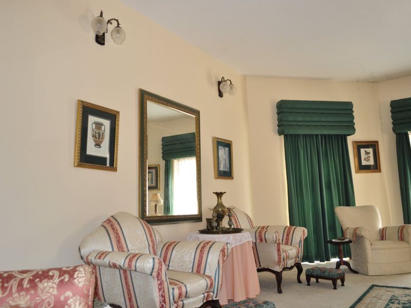 A traditional living room featuring wall-mounted light fixtures and decorative curtain pelmets, offering a classic aesthetic with neutral wall tones.