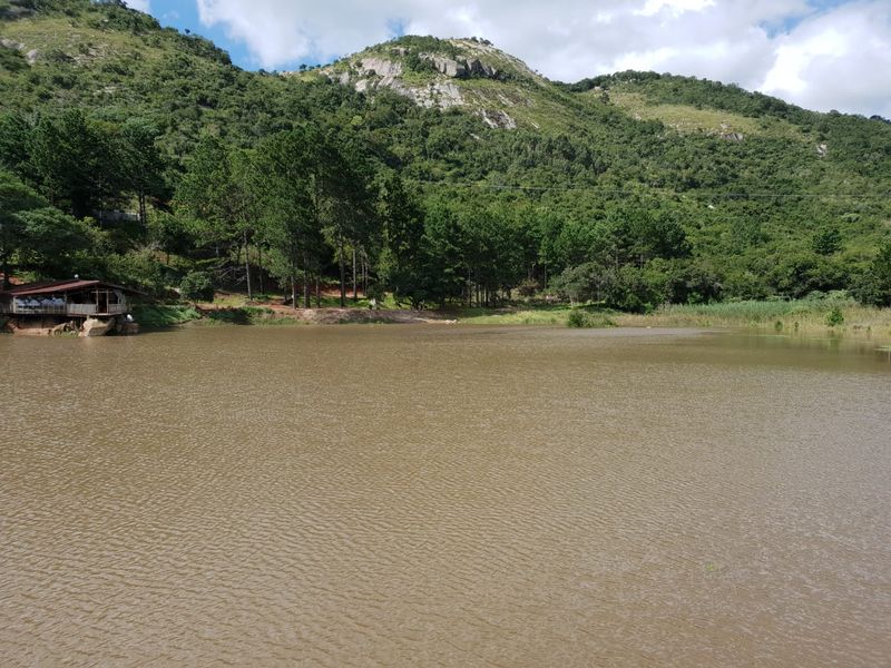 A scenic view of a large lake set against a backdrop of lush green mountains and natural landscape.