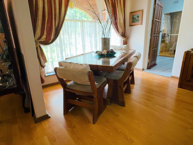 A dining room featuring laminate flooring and an arched window, providing a warm and traditional atmosphere.