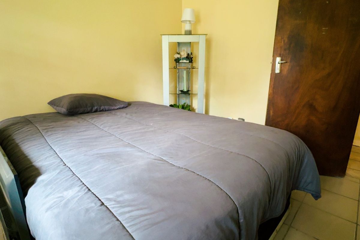 A bedroom featuring tiled flooring and a solid timber door, requiring cosmetic updates to the wall paint and door finish.
