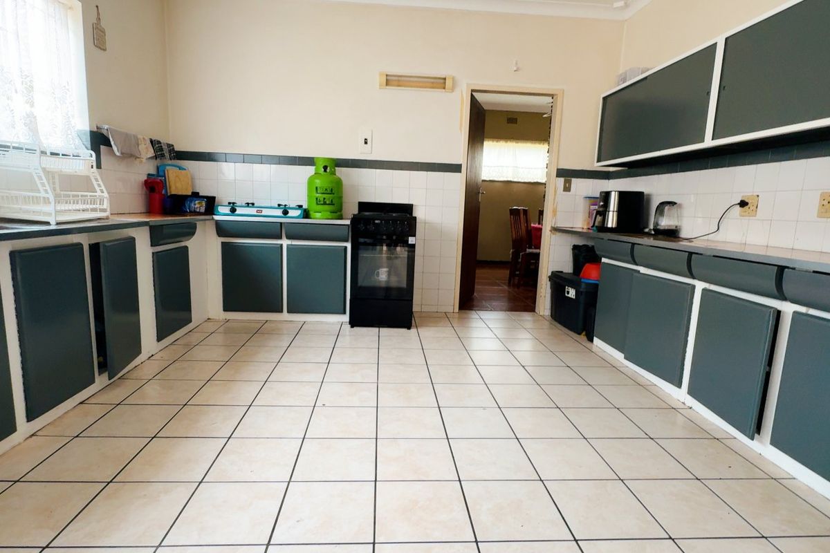 A functional kitchen featuring ample built-in cabinetry, tiled flooring, and a tiled backsplash, offering a practical layout with potential for modern updates.