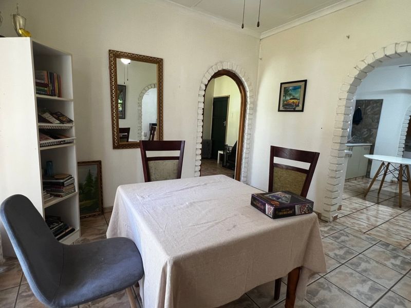 Dining area featuring tiled flooring and distinctive brick archways leading to adjacent rooms, offering a functional layout with classic architectural character.