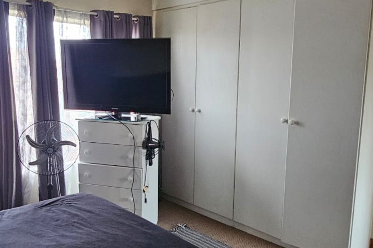 A bedroom featuring built-in cupboards and a standard ceiling light fixture, providing functional storage space.