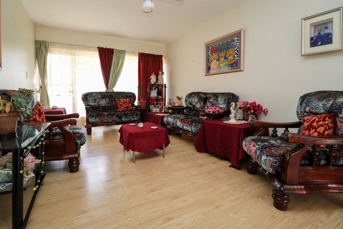 A spacious living room featuring light-toned laminate flooring, a ceiling fan, and a large sliding glass door that provides natural light.
