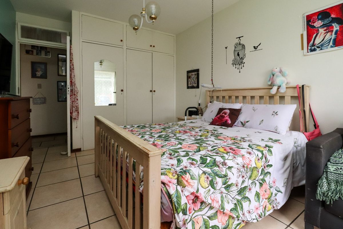 A bedroom featuring built-in cupboards and tiled flooring, offering a functional space with potential for modernization.