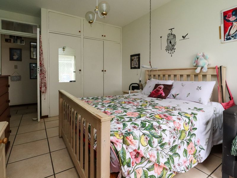 A bedroom featuring built-in cupboards and tiled flooring, offering a functional space with potential for modernization.