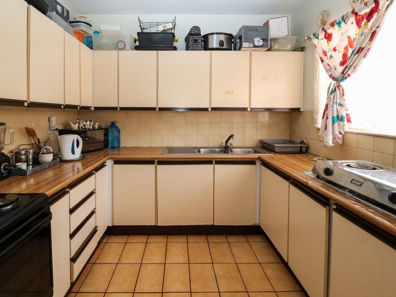 A functional kitchen featuring dated cabinetry, laminate countertops, a double basin sink, and tiled flooring, offering potential for a modern renovation.