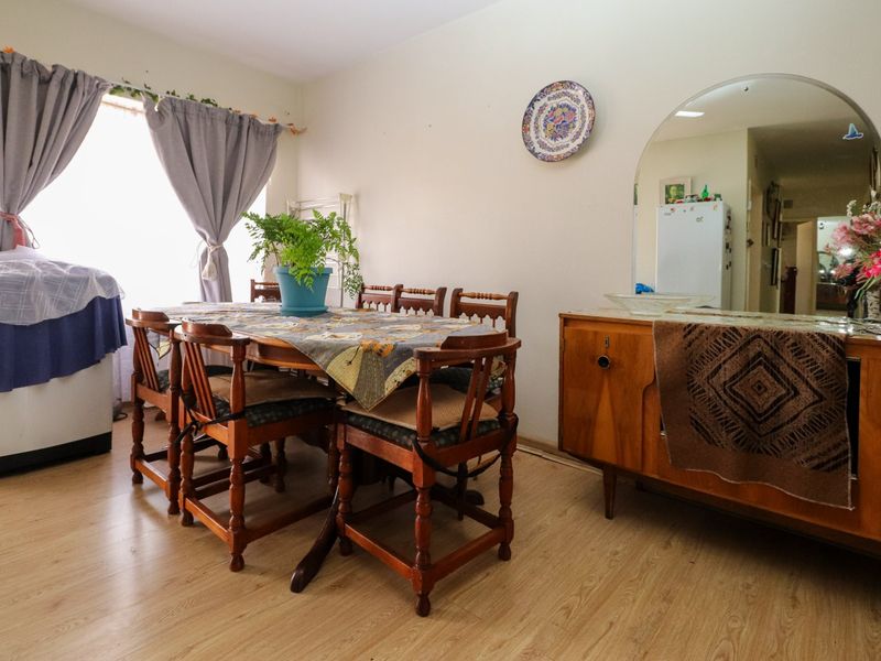 A dining room featuring light-toned laminate flooring and a large wall-mounted arch mirror, providing a functional space for meals.