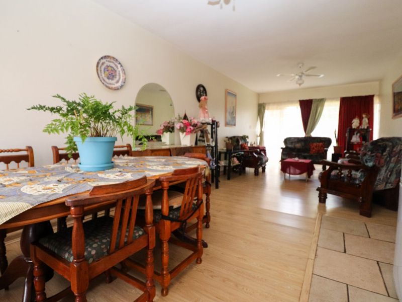 Spacious open-plan living and dining area featuring a combination of laminate and tiled flooring, ceiling fan, and access to a patio through sliding doors.
