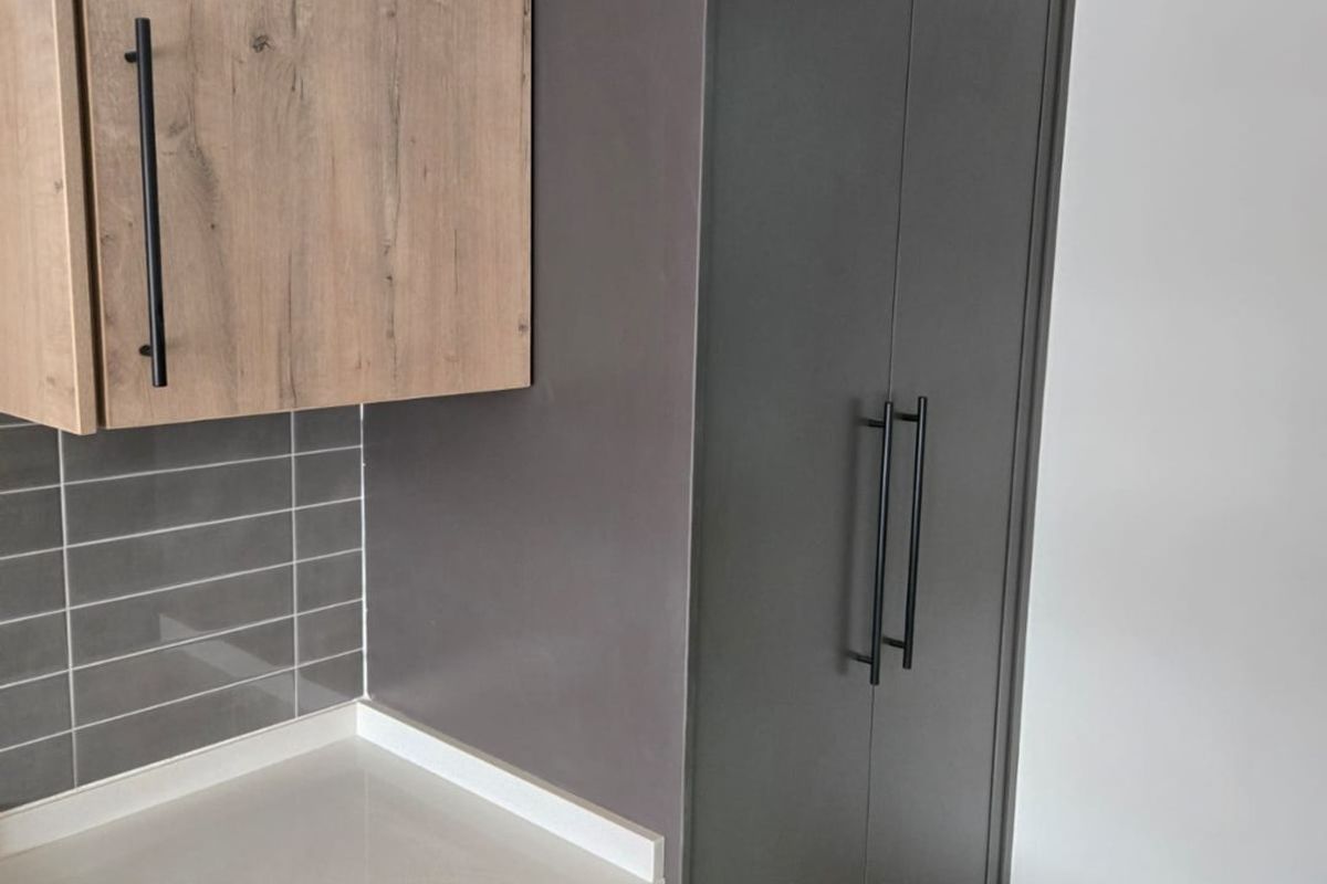Modern kitchen featuring two-tone cabinetry, stone countertops, subway tile backsplash, and a tall integrated pantry cupboard.