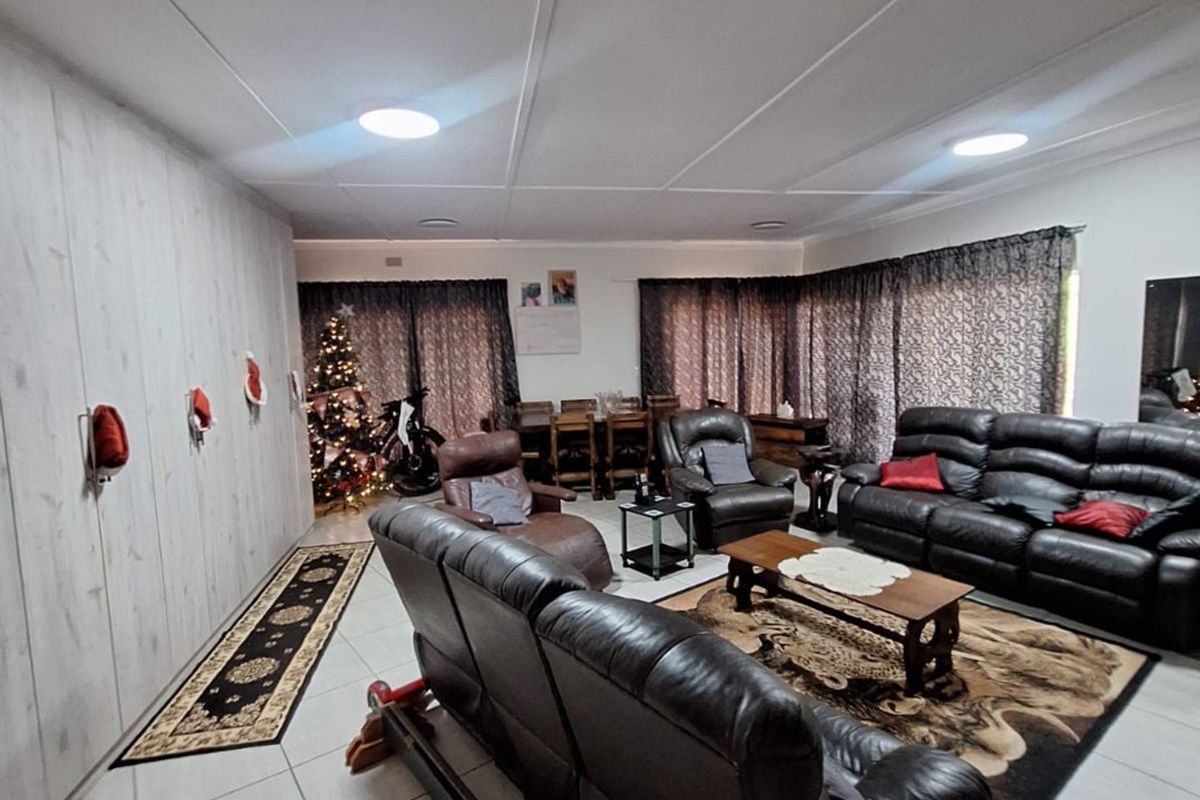 Spacious living room featuring tiled flooring and a suspended ceiling with recessed lighting, offering a functional and open layout.