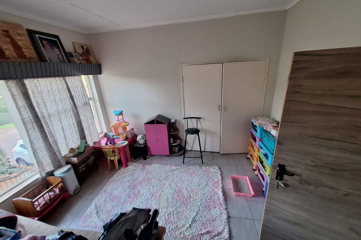 A bedroom featuring tiled flooring and built-in cupboards, providing a functional space with neutral wall finishes.