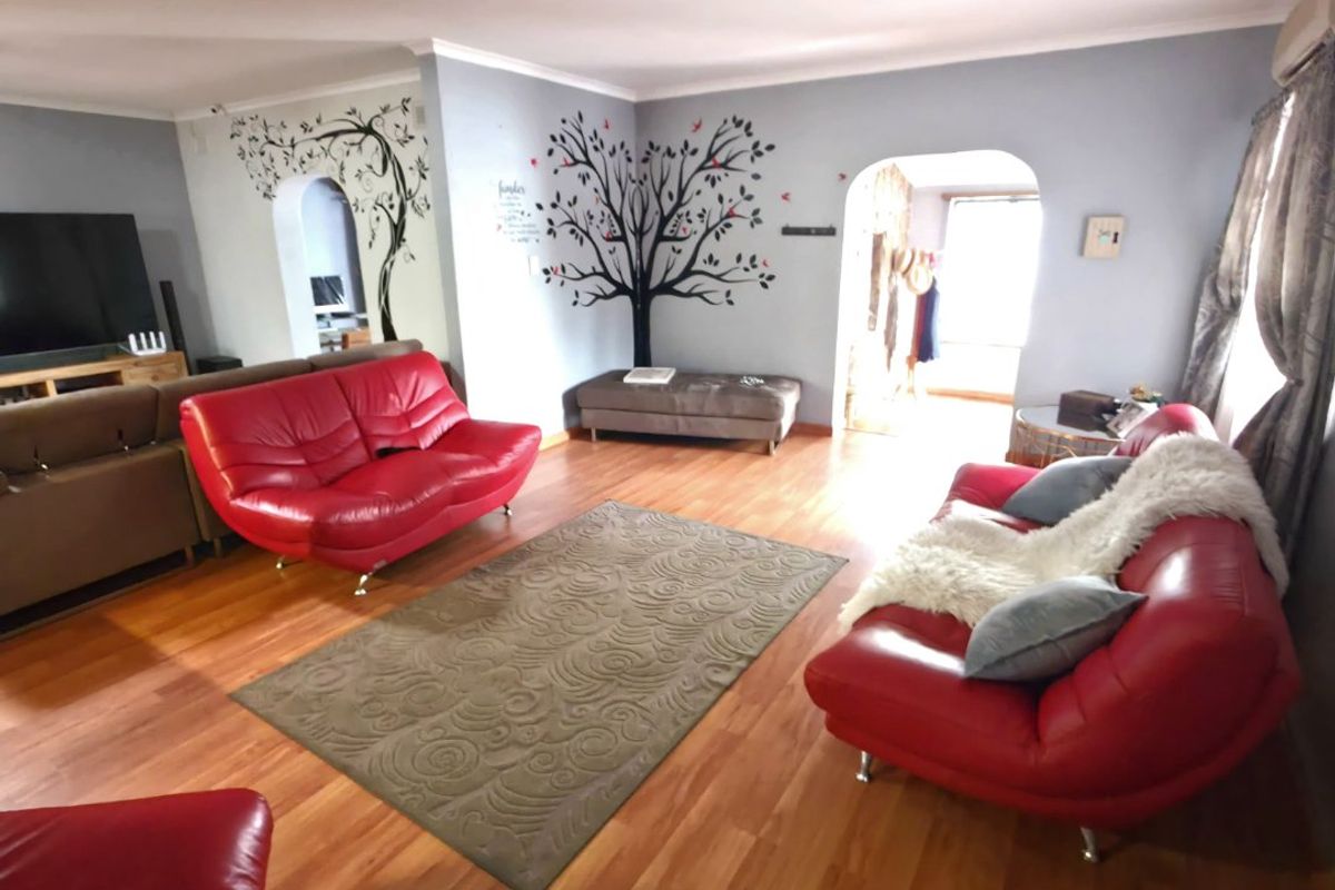 Spacious living room featuring laminate flooring and arched doorways leading to adjacent areas, providing a functional and open layout.