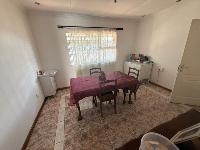 A dining room featuring tiled flooring, recessed ceiling lighting, and a wall-mounted basin, providing a functional space for meals.