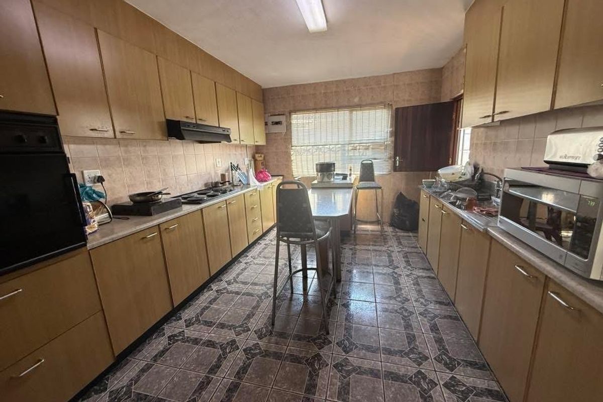 A functional galley-style kitchen featuring extensive built-in cabinetry, a built-in oven, hob, and tiled finishes throughout.