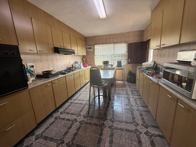 A functional galley-style kitchen featuring extensive built-in cabinetry, a built-in oven, hob, and tiled finishes throughout.