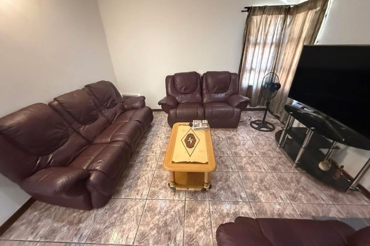 A living room featuring tiled flooring and window treatments, providing a functional space for relaxation.
