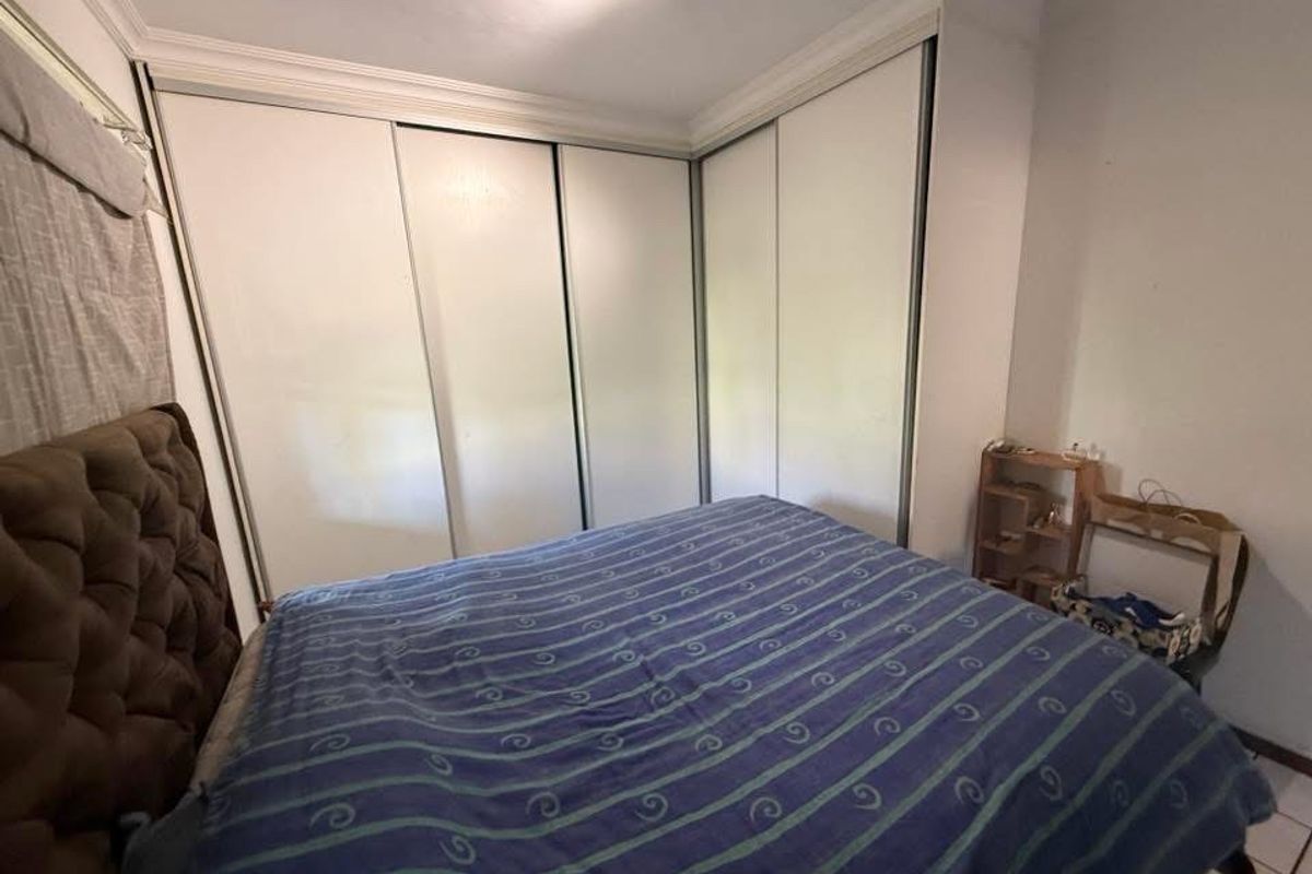 A bedroom featuring a large built-in corner wardrobe with sliding doors, crown molding, and neutral wall finishes.