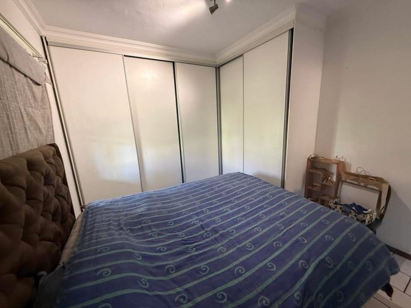 A bedroom featuring a large built-in corner wardrobe with sliding doors, crown molding, and neutral wall finishes.