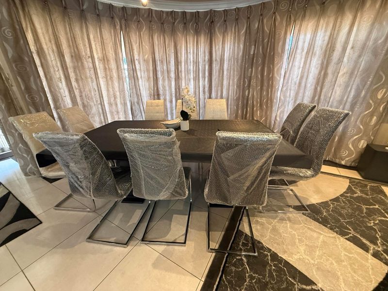 A dining room featuring tiled flooring and floor-to-ceiling curtains, providing a neutral space for formal dining.