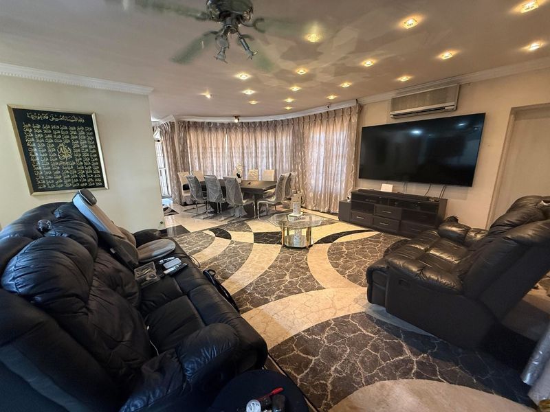 Spacious open-plan living and dining area featuring distinctive patterned marble flooring, recessed ceiling lighting, and a wall-mounted air conditioning unit.