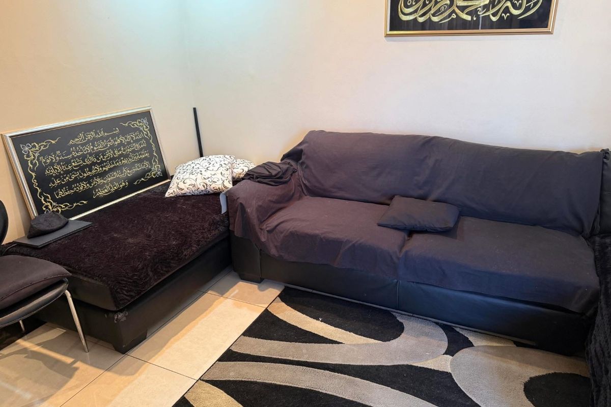 A living room area featuring neutral wall finishes and tiled flooring, providing a functional space for relaxation.